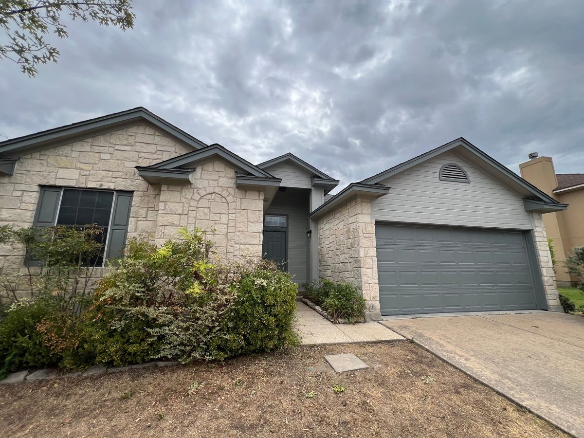Stone and siding home with freshly painted gray-green trim, siding and garage door